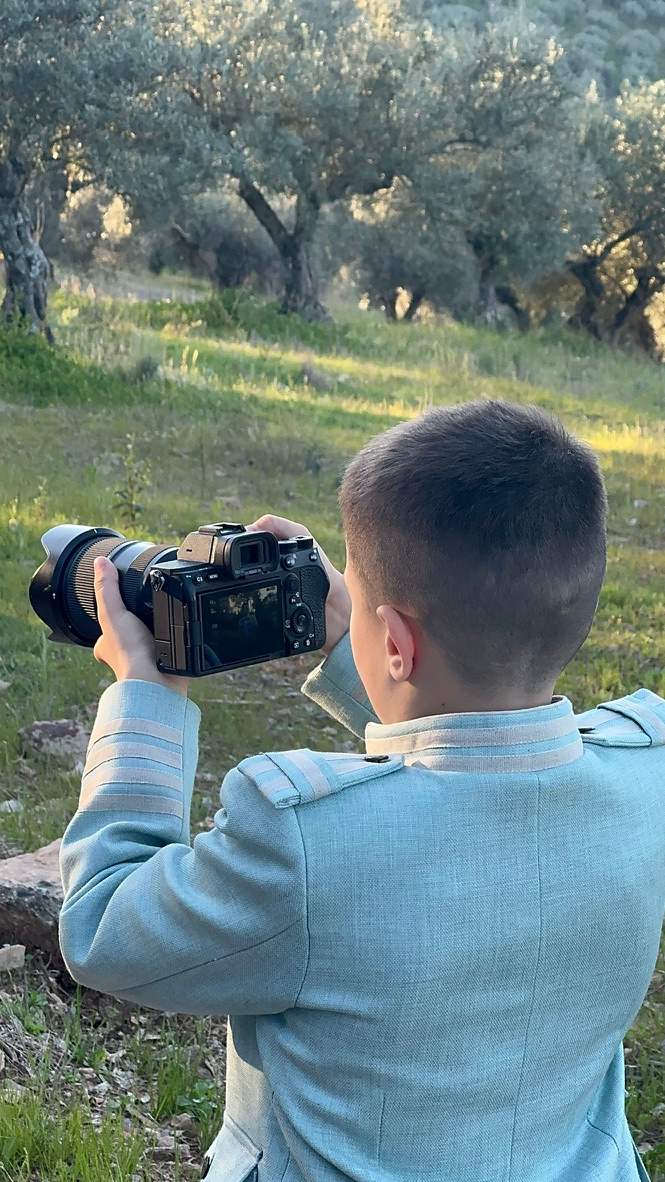 Niño vestido de comunión mirando una fotografía en la cámara durante la sesión