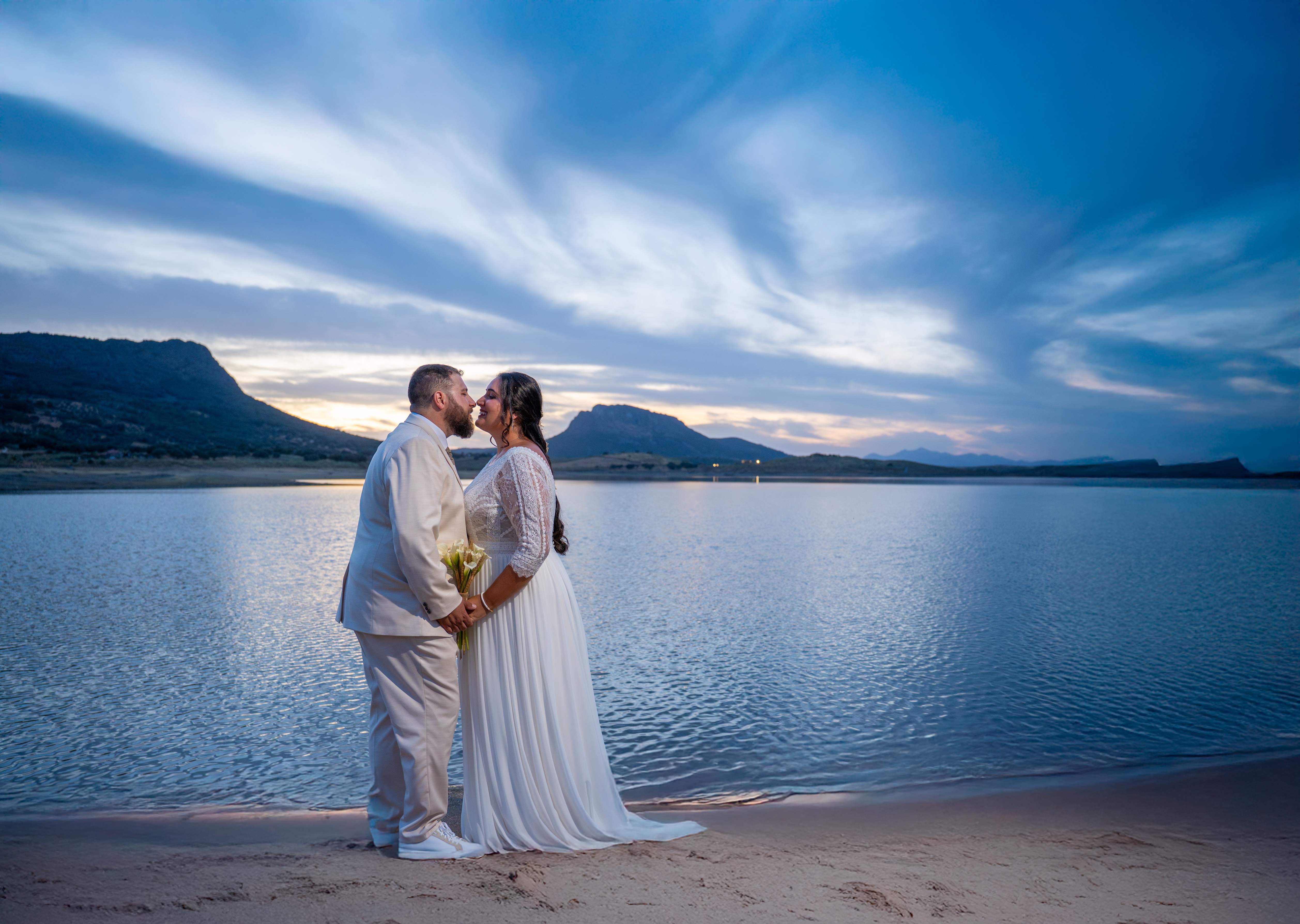 Novios abrazados al atardecer junto al embalse, en una boda fotografiada en La Siberia extremeña