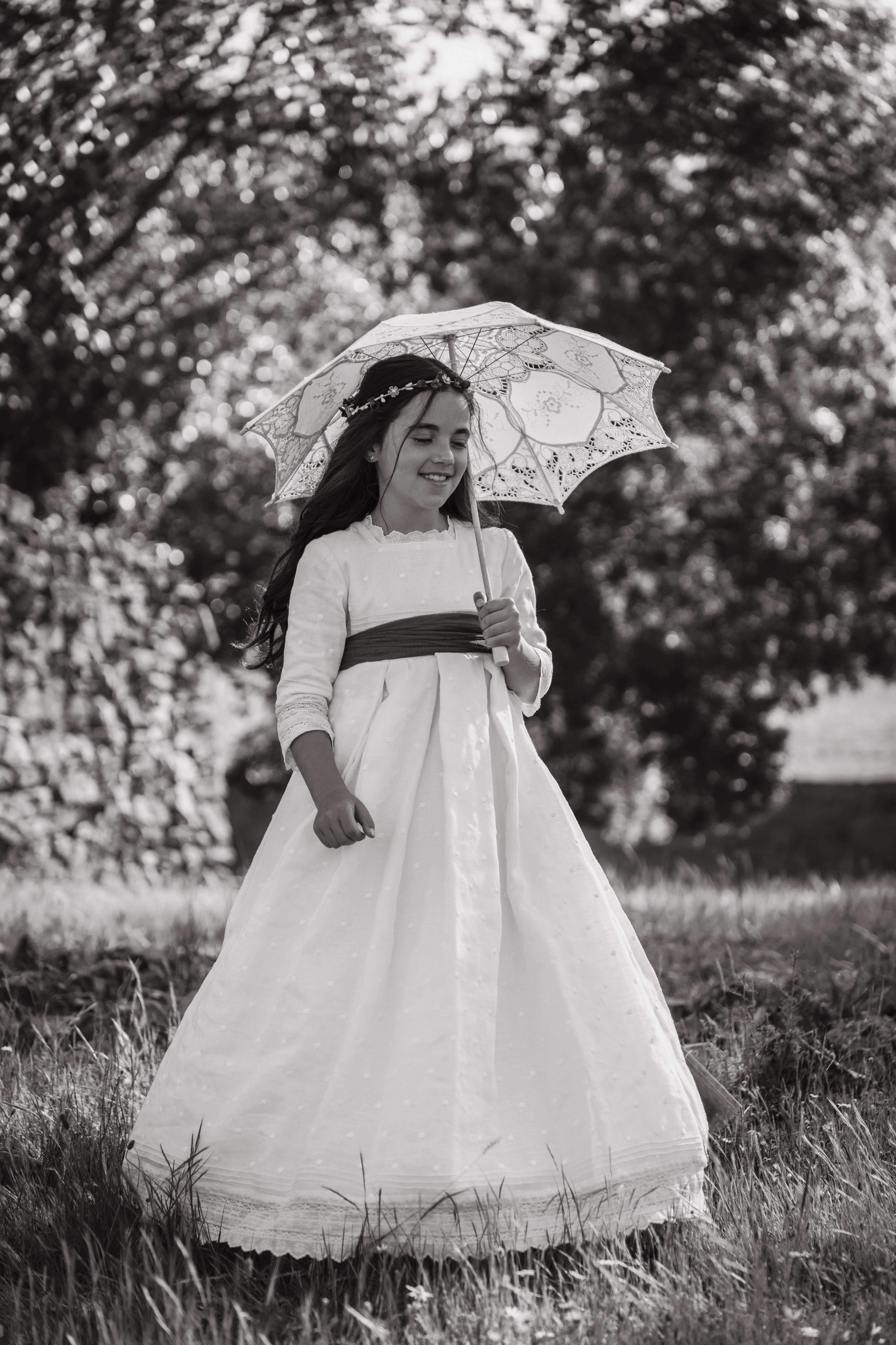 Niña con vestido de comunión y sombrilla de encaje en una fotografía en blanco y negro
