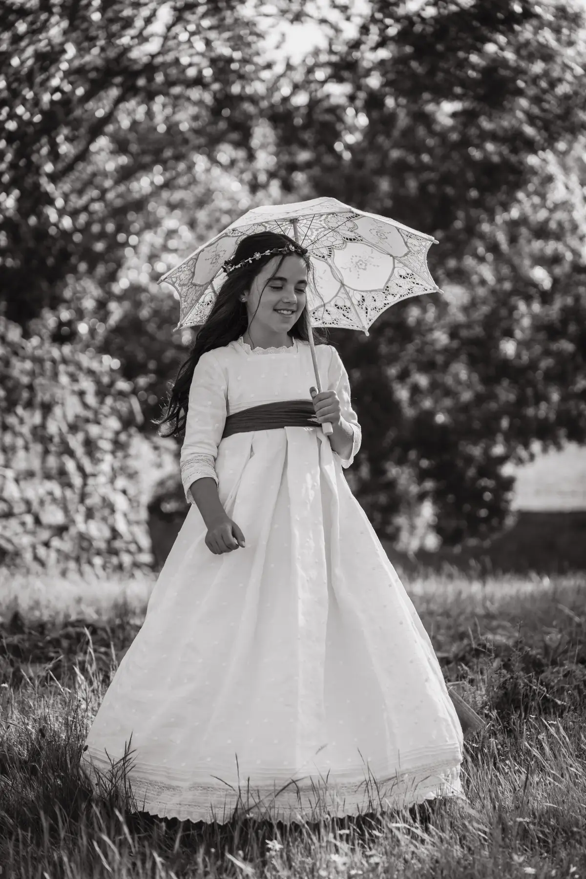 Niña con vestido de comunión y sombrilla de encaje en una fotografía en blanco y negro