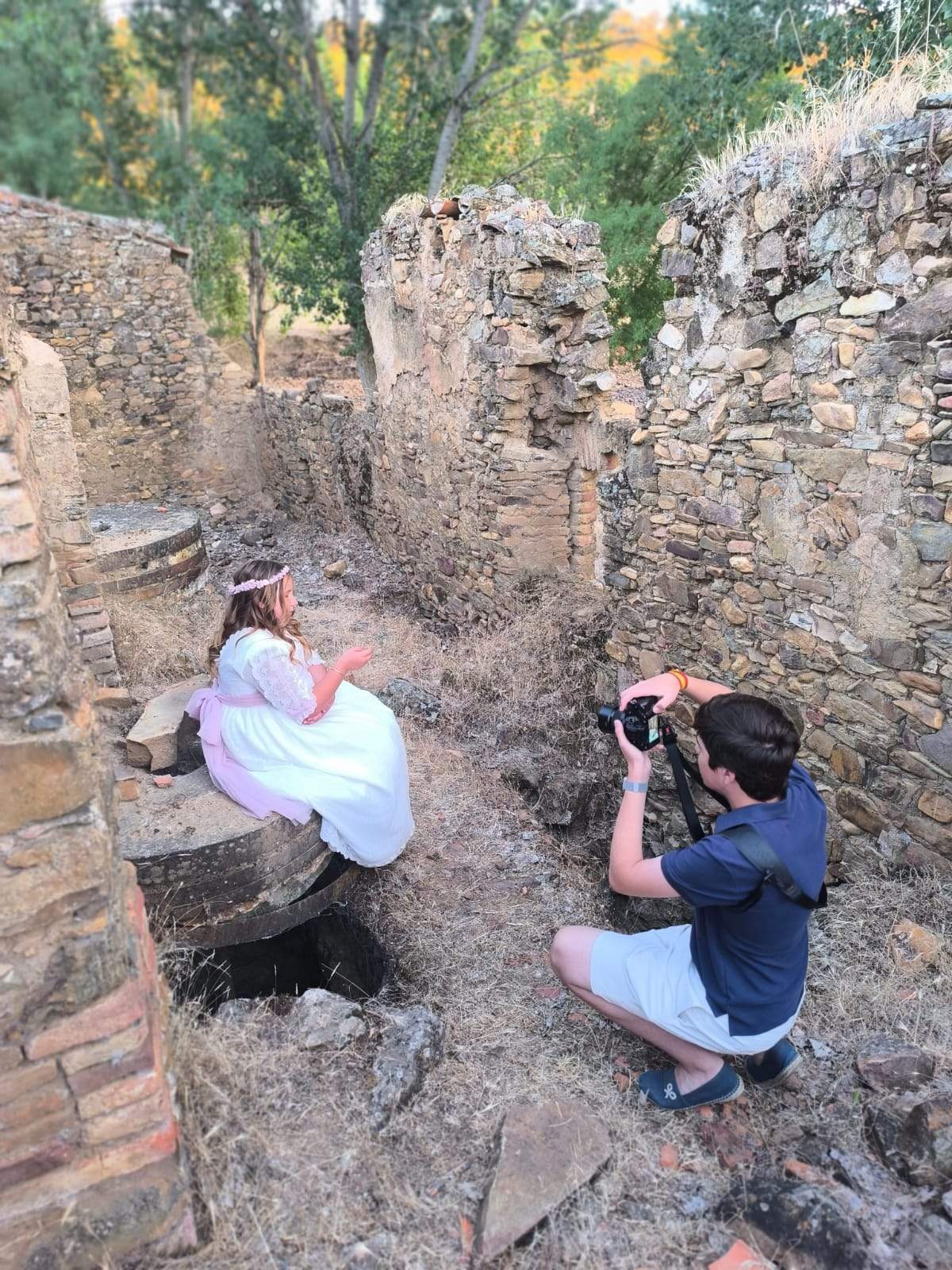 Marcos Babiano fotografiando a una niña de comunión entre muros de piedra